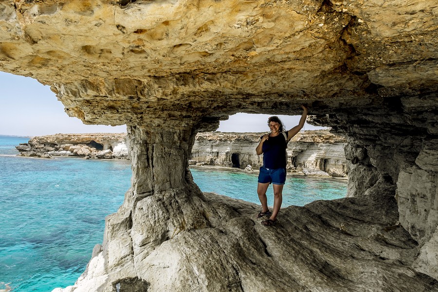 Girl posing in a rocky arch at Cape Greco. Cyprus